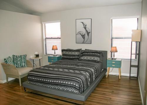 a bedroom with a bed and a chair and windows at Large Pool & Patio Cozy Single Story Family House in Las Vegas