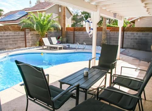 a patio with chairs and a table next to a pool at Large Pool & Patio Cozy Single Story Family House in Las Vegas