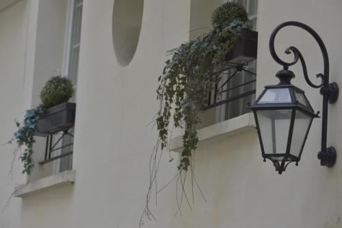 a street light attached to a building with potted plants at Unic Renoir Saint Germain in Paris
