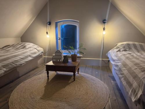 a room with two beds and a table and a window at Erve de Kippe - Logies bij de Barones in Epse