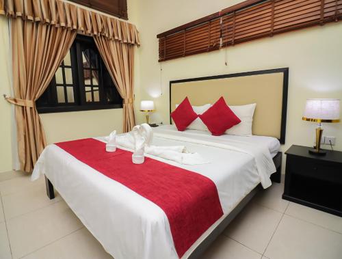 a bedroom with a large white bed with red pillows at Milan Hotel & Restaurant in Phnom Penh