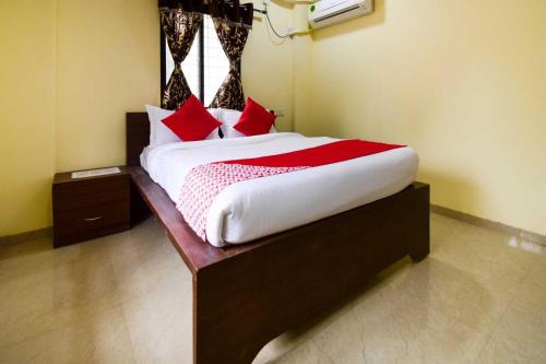 a bedroom with a large bed with red pillows at Hotel O Gokul Lodging in Pune