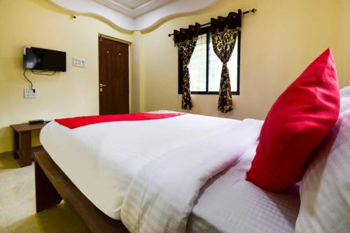 a bedroom with a bed with red pillows on it at Hotel O Gokul Lodging in Pune