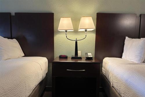 a hotel room with two beds and a lamp on a night stand at Baymont by Wyndham Tuscola in Tuscola