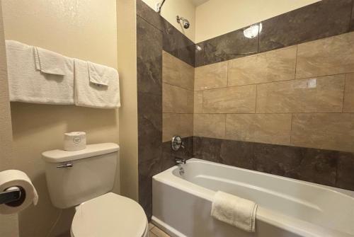 a bathroom with a toilet and a tub and a sink at Baymont by Wyndham Tuscola in Tuscola