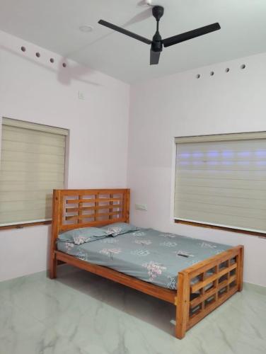 a bedroom with a wooden bed and two windows at Bluebell Shores -Cozy Stay Near Varkala Beach in Varkala