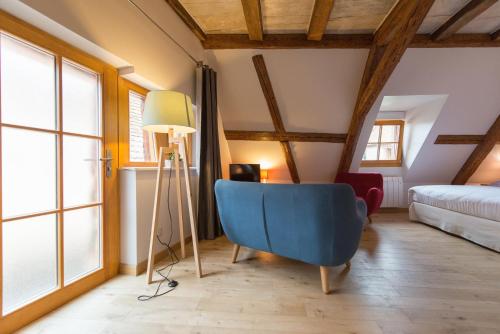 a room with a blue chair and a bed at La Maison d'Emilie in Pfaffenheim