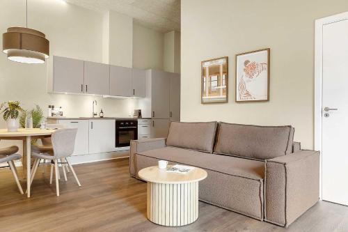 a living room with a couch and a table and a kitchen at Stylish Easy-Access Ground Floor Apartment for 4 in Aarhus