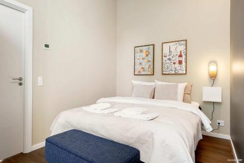 a bedroom with a large white bed with a blue ottoman at Stylish Easy-Access Ground Floor Apartment for 4 in Aarhus