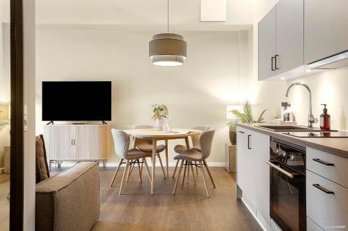a kitchen and dining room with a table and a tv at Stylish Easy-Access Ground Floor Apartment for 4 in Aarhus