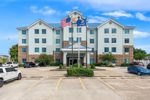 an exterior view of a hotel with cars parked in a parking lot at Comfort Suites New Orleans East in New Orleans