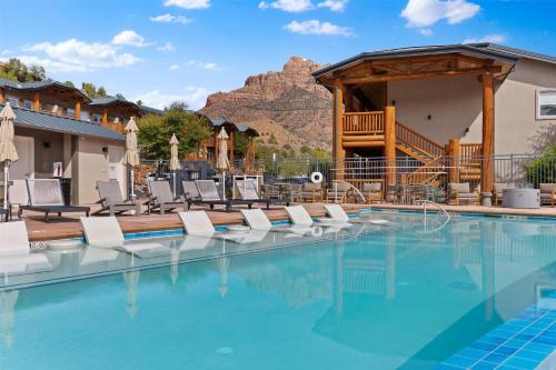 a pool with chairs and a mountain in the background at Hotel De Novo Springdale, Tapestry Collection by Hilton in Springdale