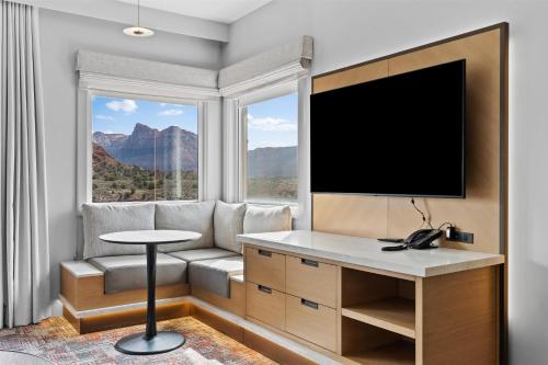 a living room with a tv and a couch and a table at Hotel De Novo Springdale, Tapestry Collection by Hilton in Springdale