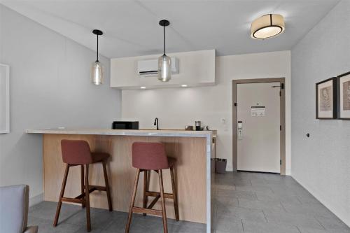 a kitchen with two bar stools and a counter at Hotel De Novo Springdale, Tapestry Collection by Hilton in Springdale