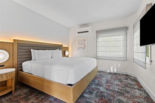 a white bedroom with a large bed and a window at Hotel De Novo Springdale, Tapestry Collection by Hilton in Springdale