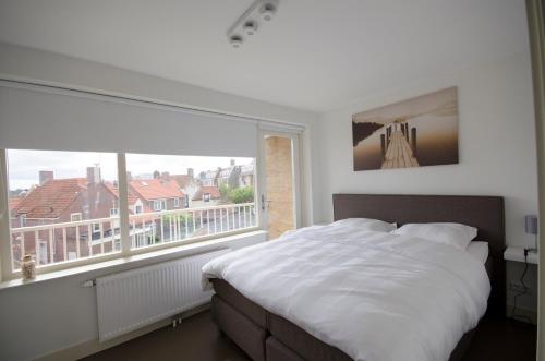 a bedroom with a bed and a large window at Flamingo Beach Apartments in Zandvoort