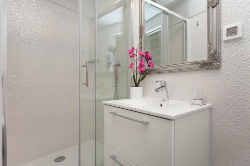 a white bathroom with a sink and a shower at Royal Apartments in Rovinj