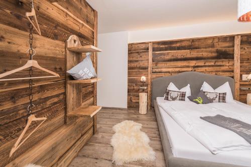 a bedroom with a bed and a wooden wall at Apartchalet Almliebe in Maria Alm am Steinernen Meer
