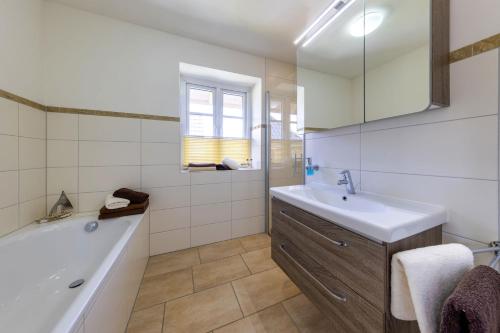 a bathroom with a tub and a sink and a bath tub at Haus Wind&Wellen, Wohnung Leuchtturm in Wittdün