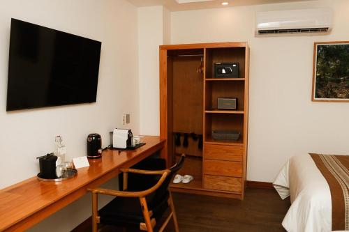 a bedroom with a desk with a television and a bed at Hotel Téneka in Xilitla