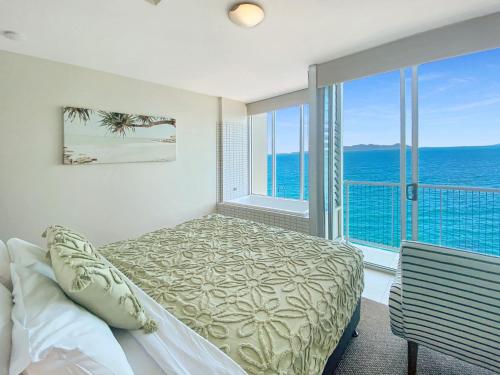a bedroom with a bed and a view of the ocean at 1 Bright Point Apartment 4305 in Nelly Bay