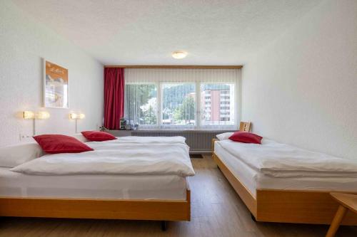 two beds in a room with a window at Hostel Casa Franco in St. Moritz