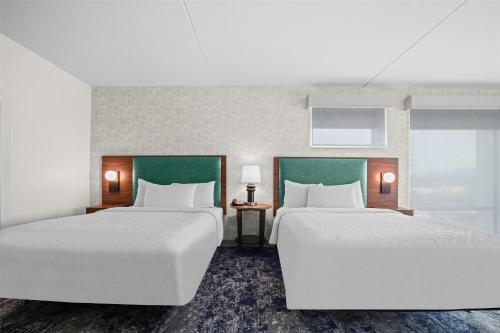 two beds in a hotel room with white sheets at Home2 Suites By Hilton Pigeon Forge in Pigeon Forge