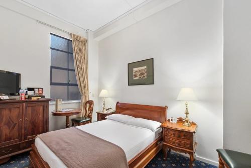 a bedroom with a bed and a desk and a television at Castlereagh Boutique Hotel, an Ascend Collection Hotel in Sydney