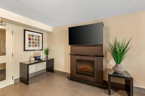 a living room with a fireplace and a flat screen tv at Comfort Inn in Brantford