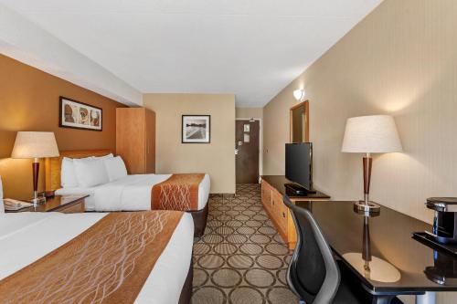 a hotel room with two beds and a desk with a television at Comfort Inn in Brantford