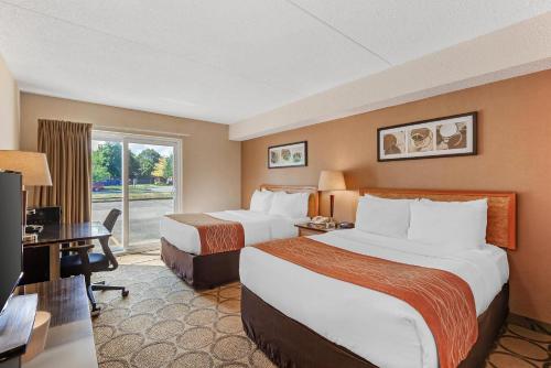 a hotel room with two beds and a desk at Comfort Inn in Brantford