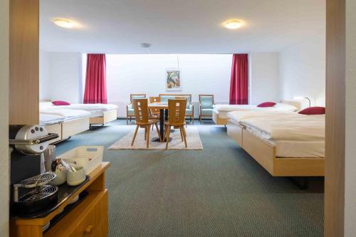a hotel room with two beds and a table and chairs at Hostel Casa Franco in St. Moritz