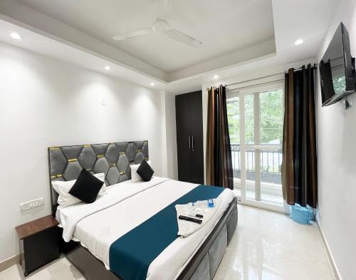 a bedroom with a large bed and a flat screen tv at Hotel 24 Near DLF Avenue in Jāmb