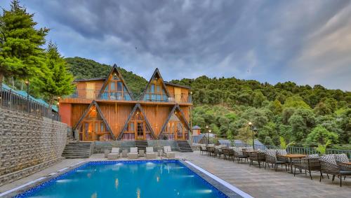 a house with a swimming pool in front of a building at Dreamation Resorts in Bīr