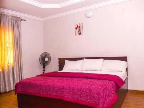 a bedroom with a large bed with a red blanket at Rikkies Place Hotel in Lagos