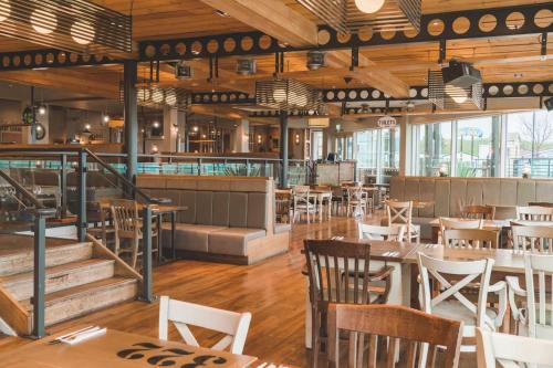 a restaurant with wooden tables and chairs and windows at A&L Holiday Home Craigtara in Ayr