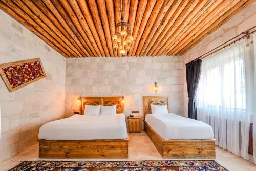 two beds in a room with a large window at MDC Cave Hotel in Urgup
