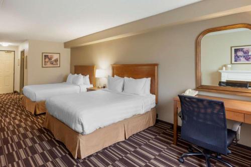 a hotel room with two beds and a desk at Best Western Plus Orillia Hotel in Orillia