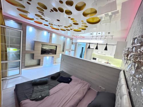 a bedroom with a large bed and a kitchen at Уютная квартира in Almaty