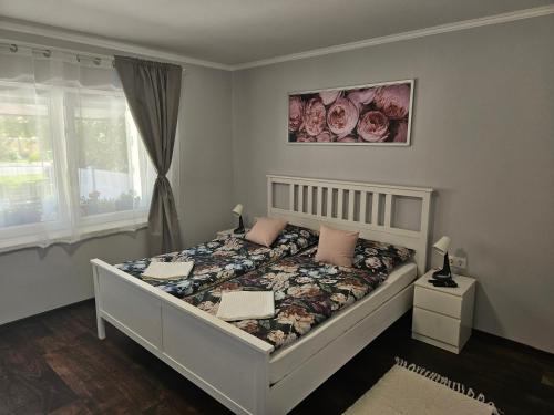 a bedroom with a white bed with pink pillows at Dolce Vita Apartman Gyula in Gyula