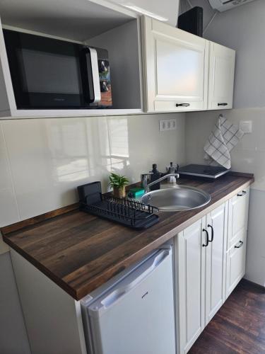 a kitchen with a sink and a microwave at Dolce Vita Apartman Gyula in Gyula