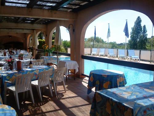 ヴァンスにあるMas de Vence - Hotel-Restaurantのスイミングプールのそばのレストラン(テーブル、椅子付)