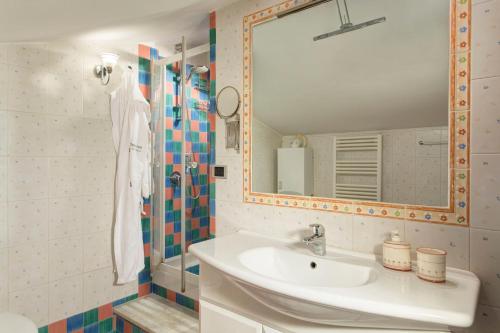 ein Bad mit einem Waschbecken, einem Spiegel und einer Dusche in der Unterkunft Tetto Fiorito in Castellammare di Stabia