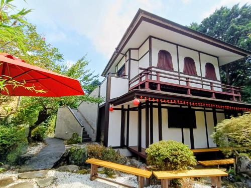 a house with a red umbrella and a bench at Ryuuei in Kawazu