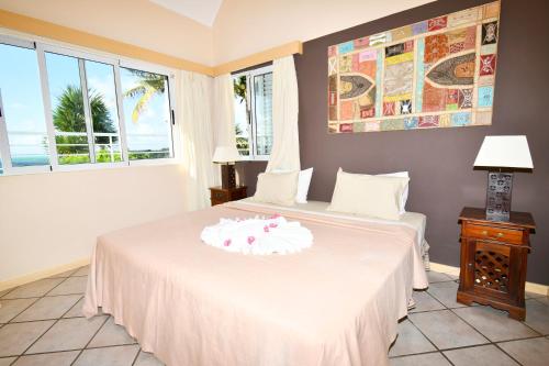 a bedroom with a white bed with a table and windows at THE BAY in Trou dʼ Eau Douce