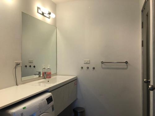 Un baño con lavabo y un espejo grande. en GrandBlue Condo 506, en Ban Tha Fat