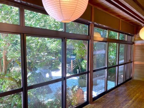 a room with large windows looking out onto a garden at Ryuuei in Kawazu