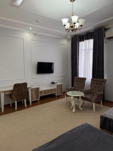 a living room with a tv and a couch and a table at GRAND SARBON HOTEL in Qarshi