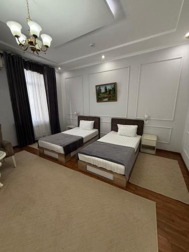 a bedroom with two beds and a chandelier at GRAND SARBON HOTEL in Qarshi