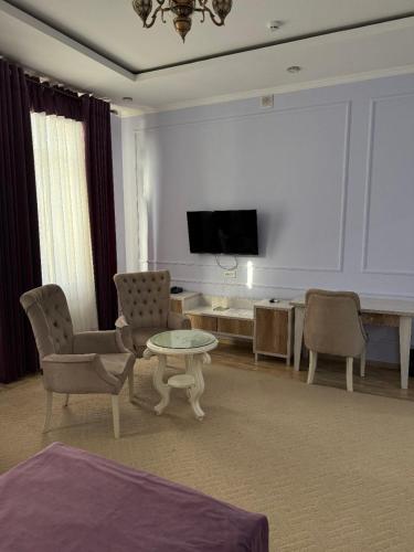 a living room with a tv and a table and chairs at GRAND SARBON HOTEL in Qarshi